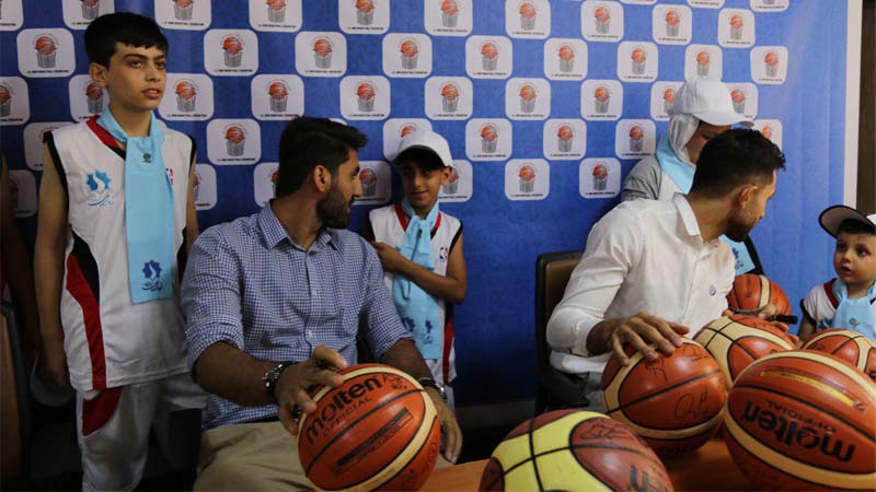 اعضاء تیم ملی بسکتبال ایران در حال امضاء توپ برای هدیه به کودکان بنیاد نیکوکاران راه آسمان